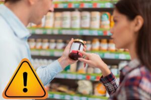 donna che sceglie marmellata al supermercato e segnale di pericolo